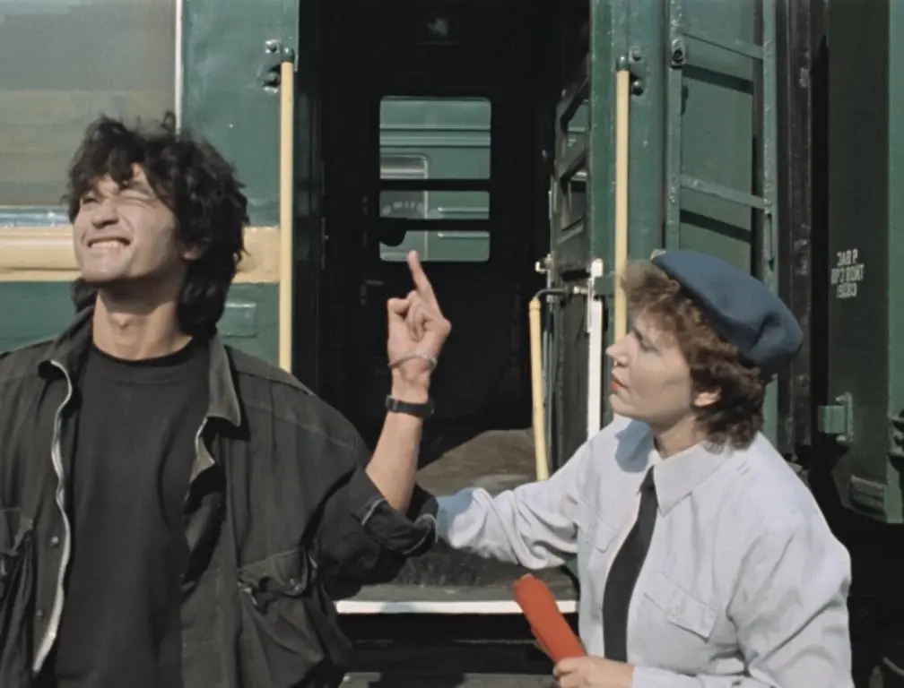 Screencap from 1988 film The Needle: Moro, played by Viktor Tsoi, just departed from a train, is flipping off a woman grabbing his arm.