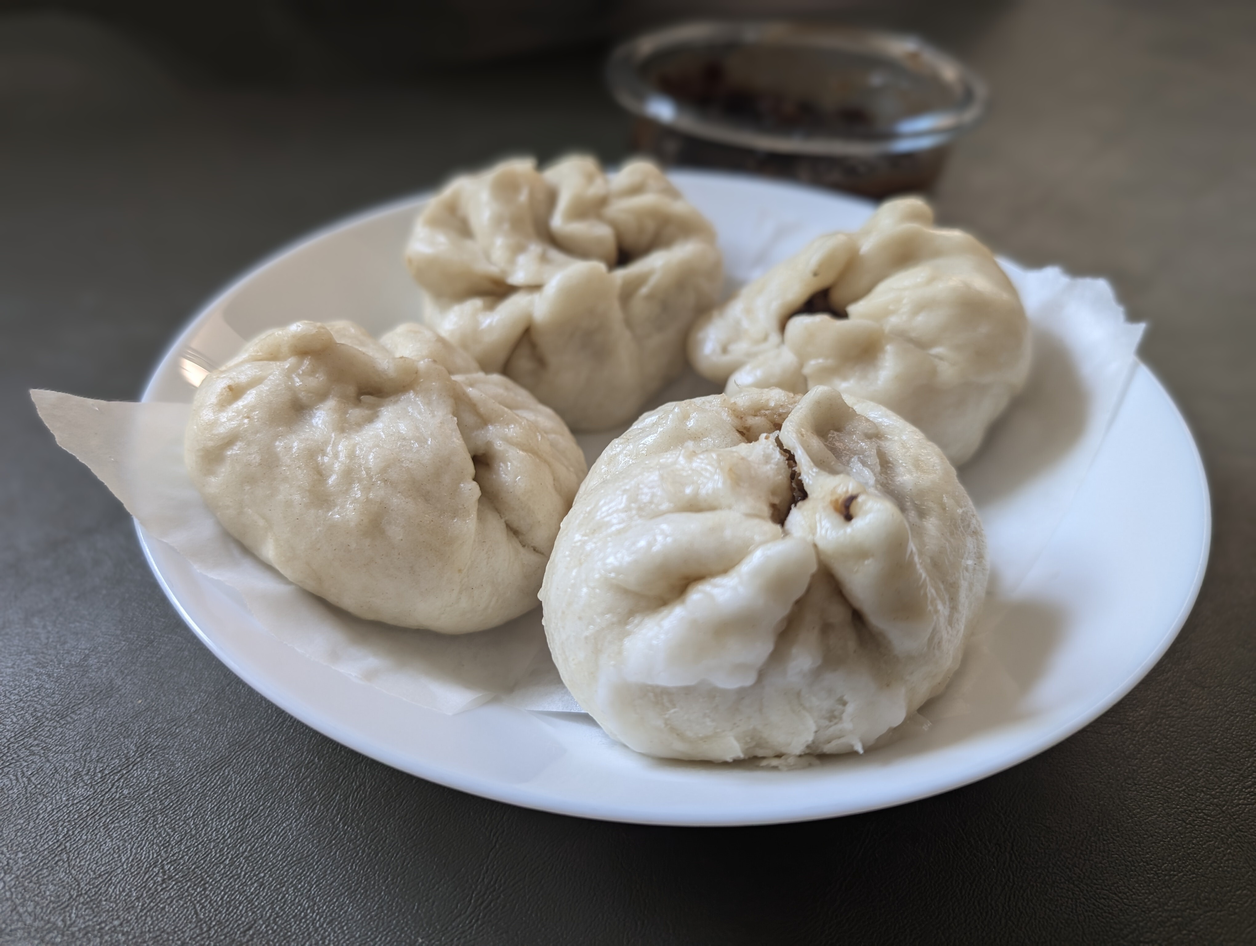 four siopao (steamed buns) arranged on a white plate.