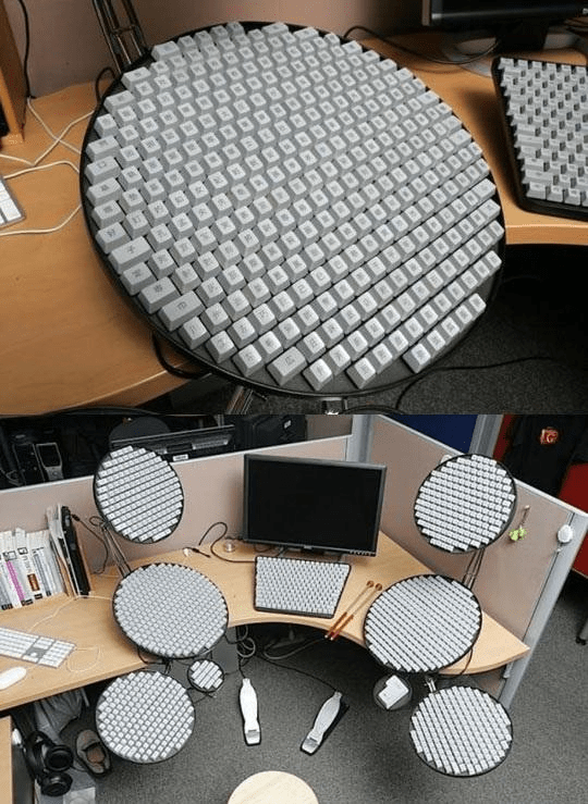 The upper image shows a circular keyboard - that is a literal circle with a 20 key diameter - with Chinese characters on the keys. The lower image shows a single office cubicle with six of those circle keyboards around a monitor with the center keyboard having a trapezoid shape. I'd estimate there are more than 1000, closer to 2000 keys on all seven keyboards combined. 