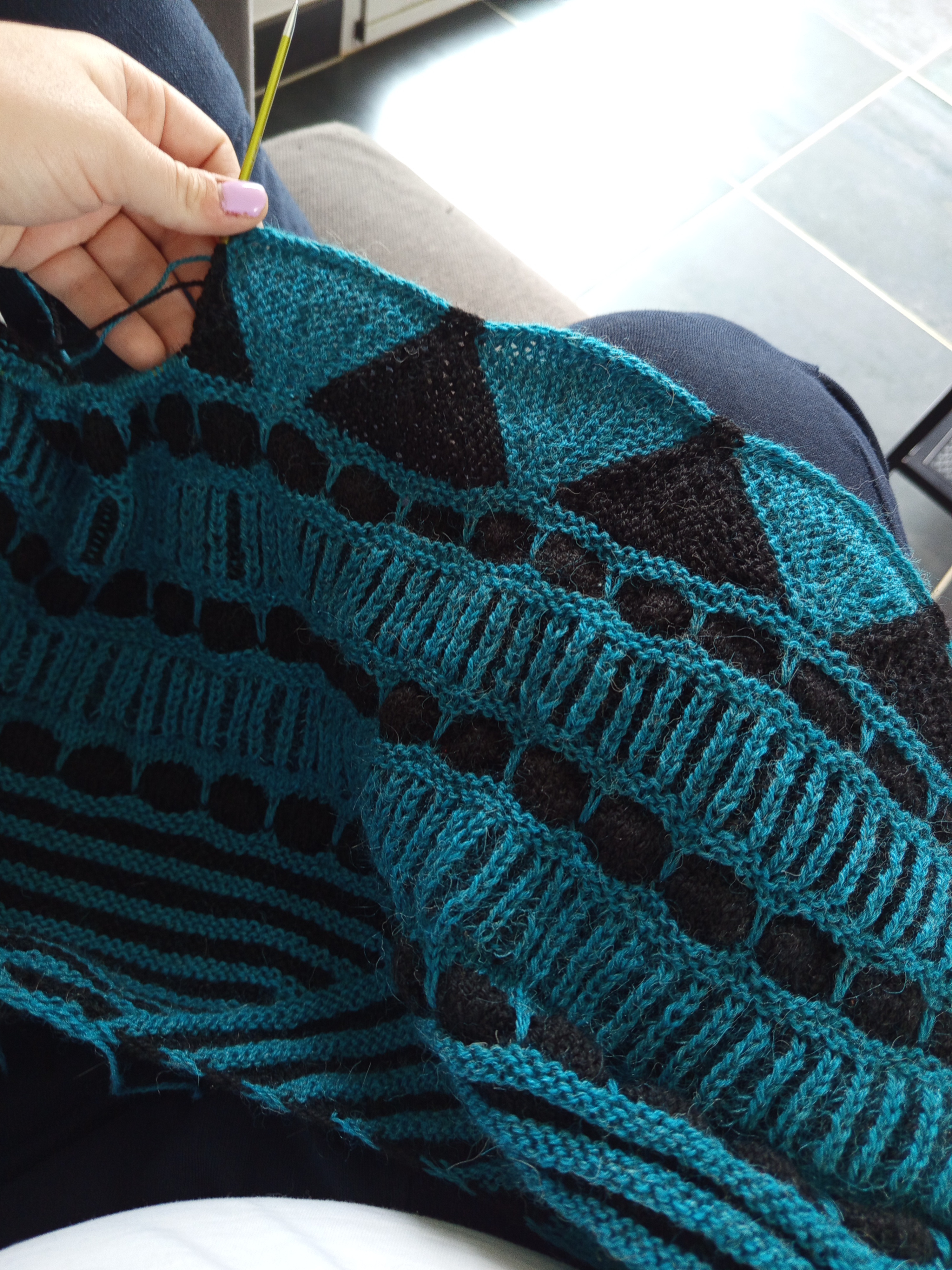 châle bleu et noir en cours de tricot d'après un patron de Stephen West (Gogo Dynamo)